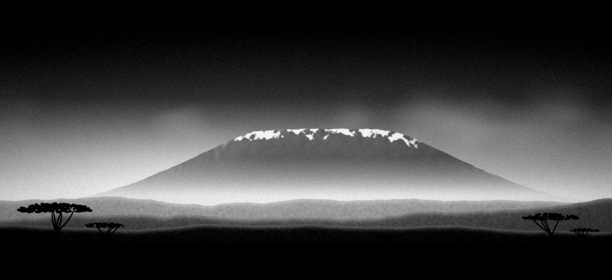 Black and white landscape: a snow-capped mountain over the plains at the edge of the savanna